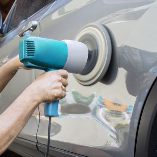 Hands polish a car body with polisher