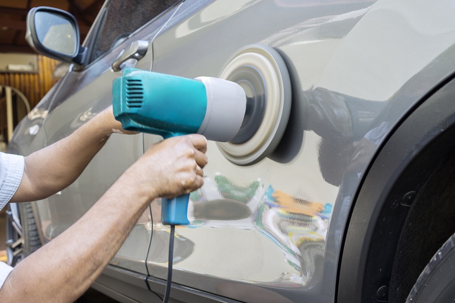 Hands polish a car body with polisher